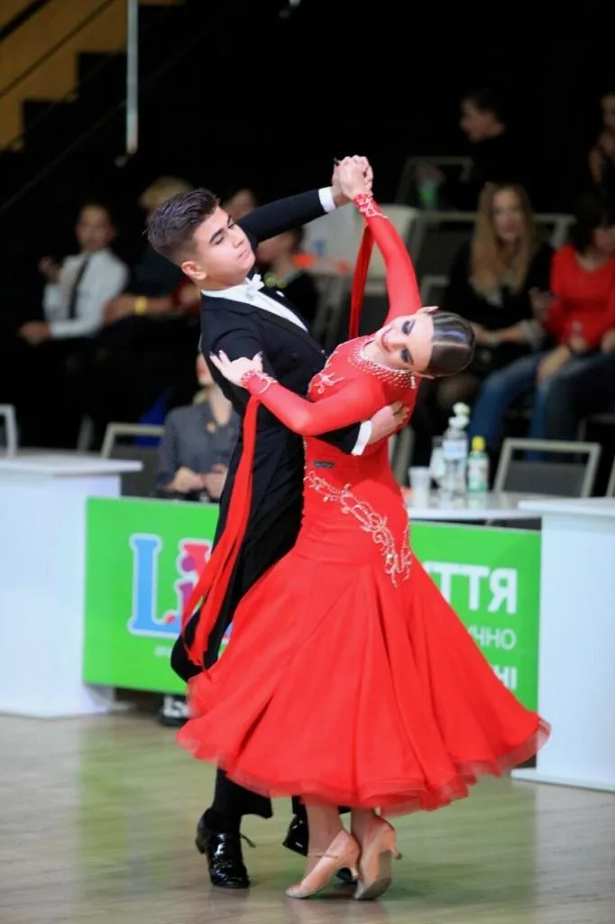 Maryan ballroom dancing with a partner in a red dress